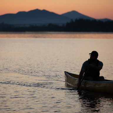 A solo paddler at sunset with the mountains in the back