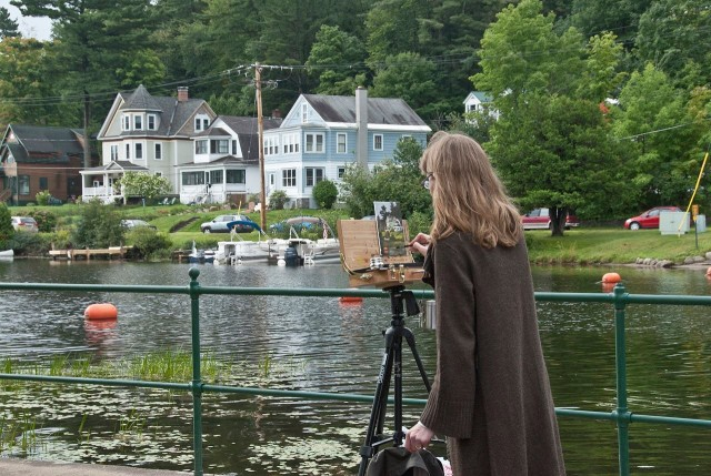 ​​A woman paints at an easel at the shore of Lake Flower during the Plein Air Festival, one of the Adirondack art shows in Saranac Lake