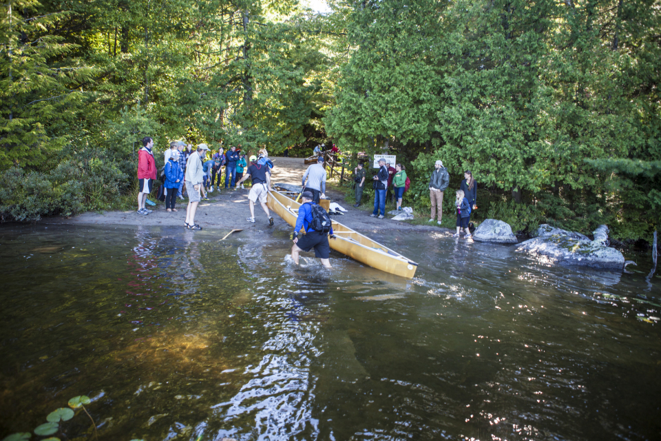 Spectators watch twoAdirondack Canoe Classic athletes leave the water during one of the carries in the race