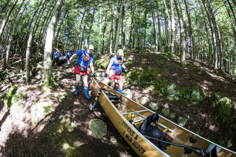 A team navigates one of the carries with their canoe in the Adirondack Canoe Classic