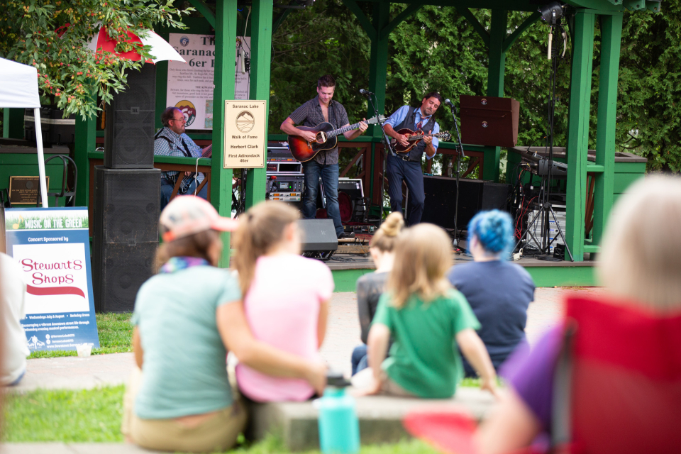 a band plays for a large crowd in the park