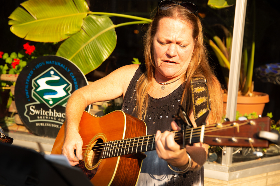 woman plays guitar on the sidewalk