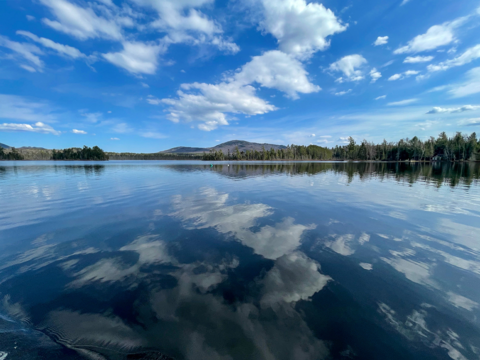 Perfectly calm waters reflect back an image of clouds and a mountain.