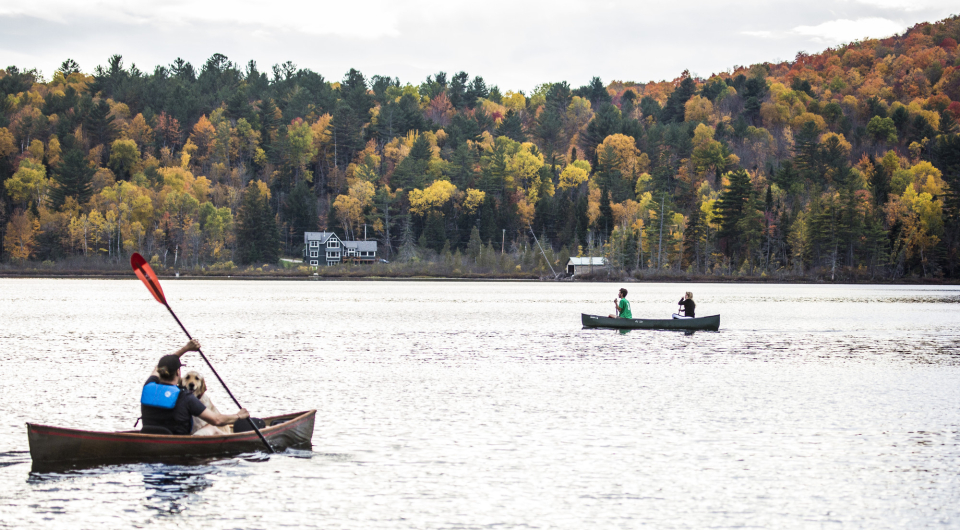 Two canoes participating in the 'Round the Mountain Canoe Race with beautiful fall foliage in the background.