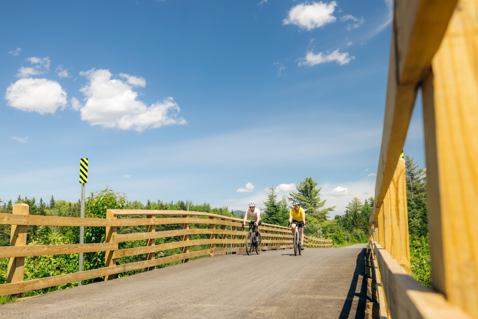 Two people bike a paved bridge.