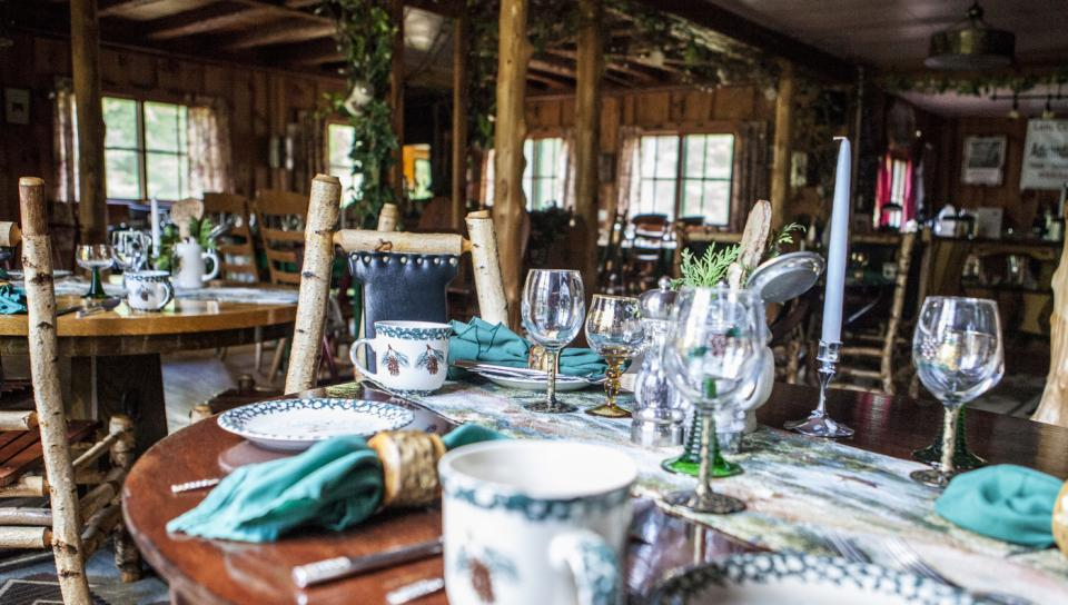 A woodsy inn filled with dining tables and eclectic place settings.