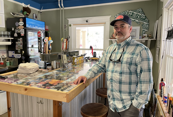 A man stands at a handcrafted bar.