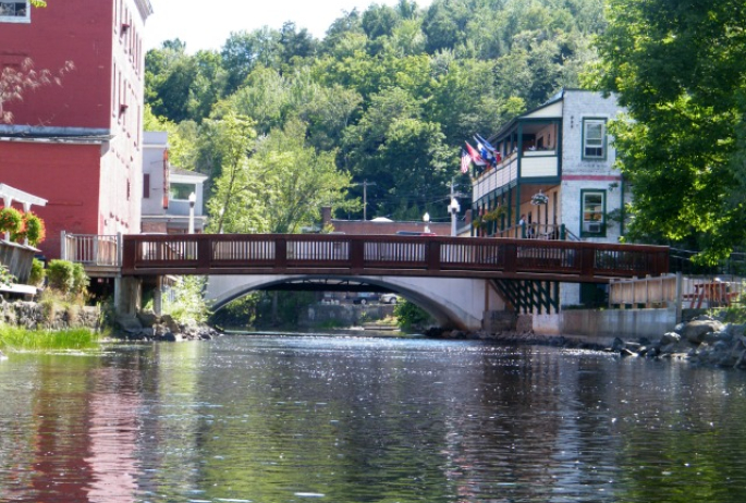 View of a bridge from the center of the Saranac River in downtown Saranac Lake