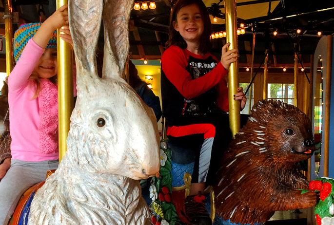 Smiling children riding on the Adirondack Carousel.