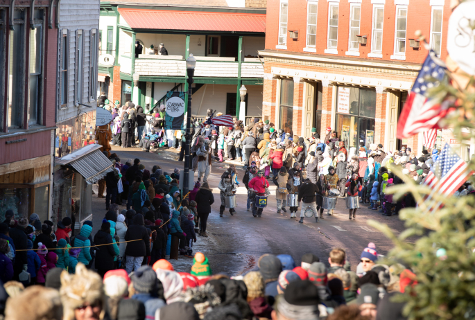 A parade of people on a winding downtown street during winter.