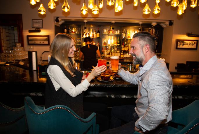 A man and woman share drinks at an upscale bar.