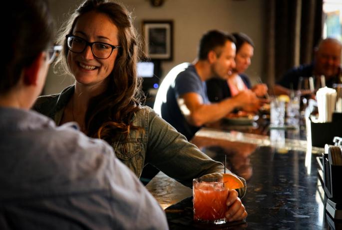 A woman laughs at a bar with a friend.