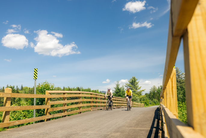 Two people bike a paved bridge.