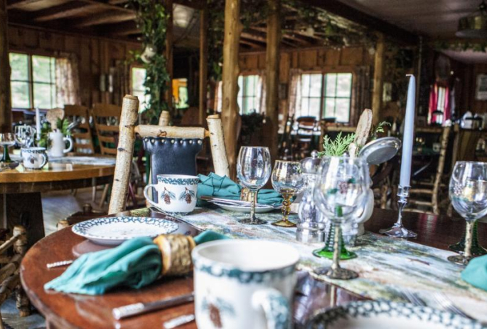 A woodsy inn filled with dining tables and eclectic place settings.