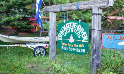 The green sign for Raquette River Outfitters